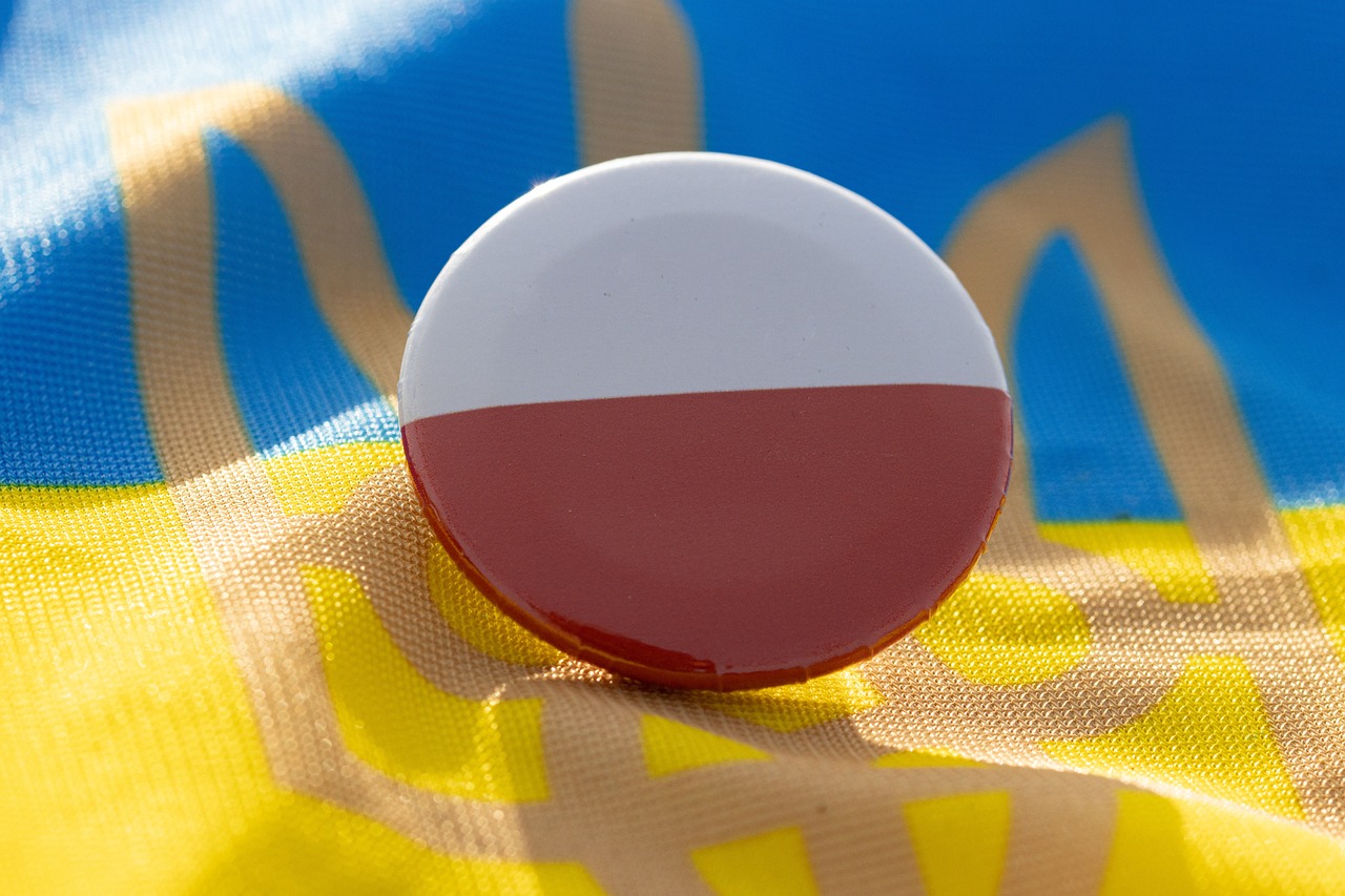 Przypinka w polskich barwach narodowych umieszczona na fladze Ukrainy.